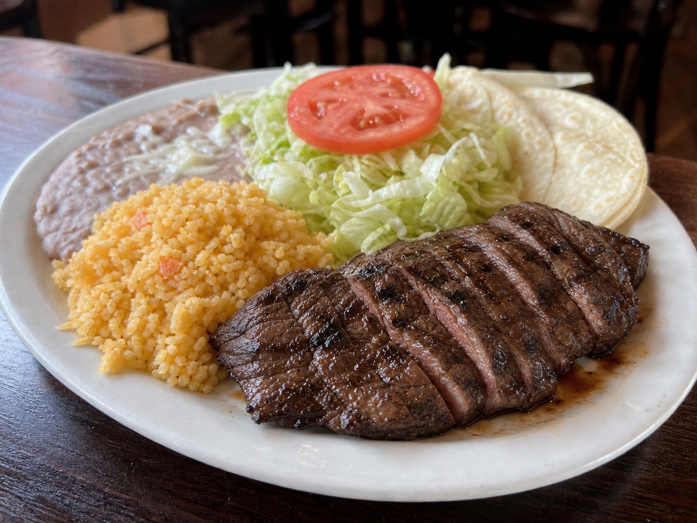 Carne asada with Mexican rice, refried beans, salad, and tortillas